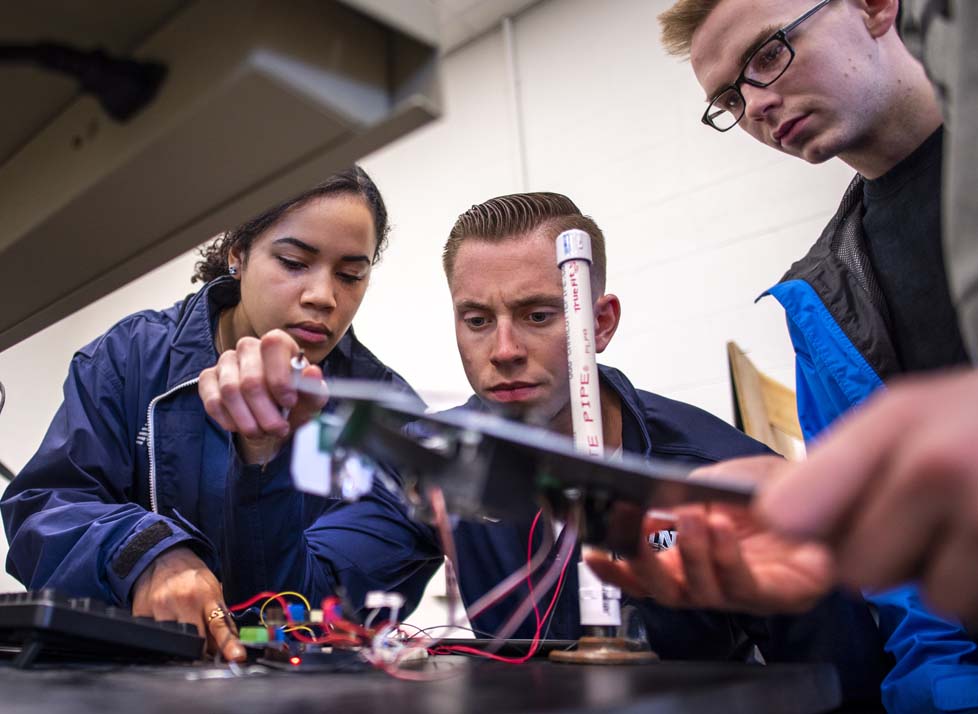A photo of three people in an engineering lab