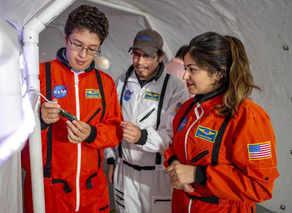 A photo of three people in jumpsuits in a lunar habitat