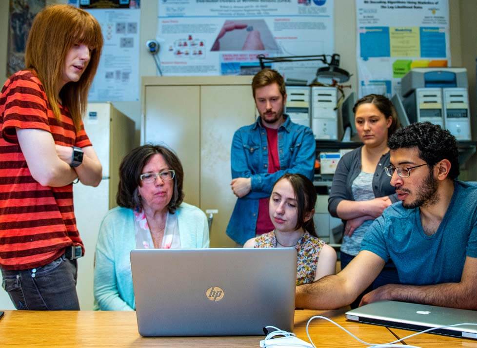 A photo of a group of students looking at a laptop