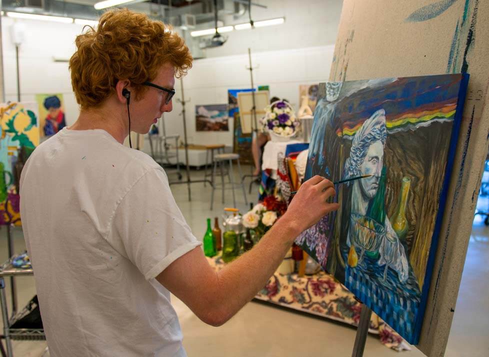 A photo of a student artist painting on a canvas