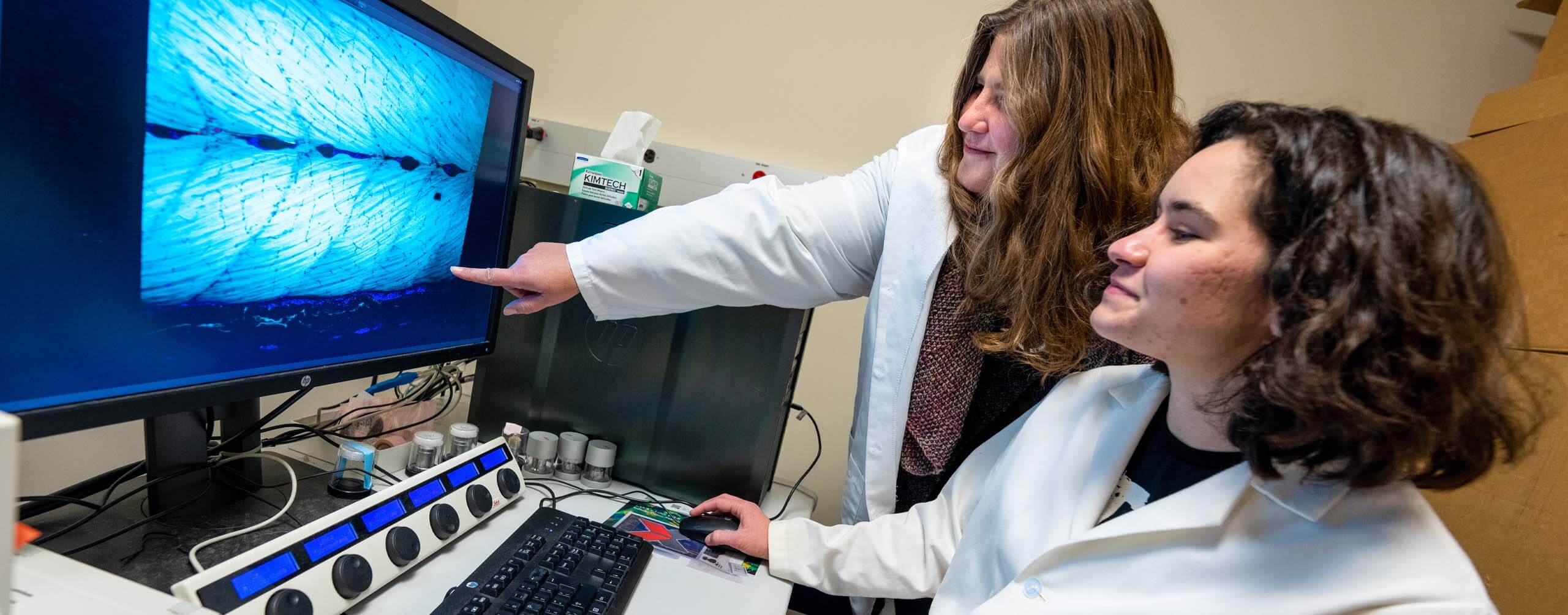 A photo of a student and professor in a lab, looking at a computer
