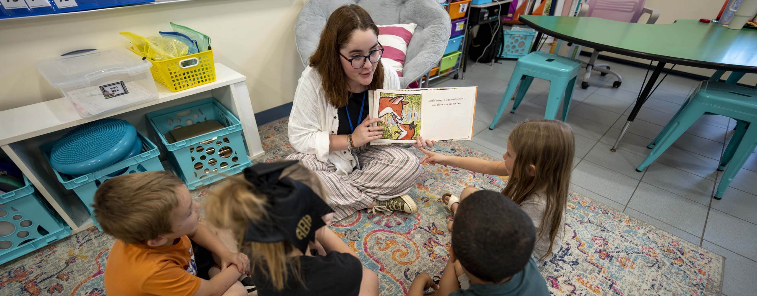 A photo of a student-teacher working with young students