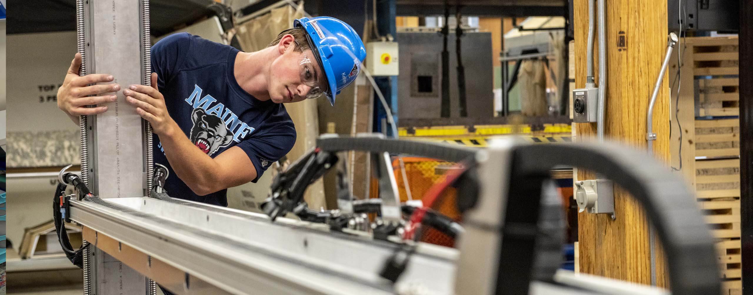 A photo of a student in a lab wearing a hard hat