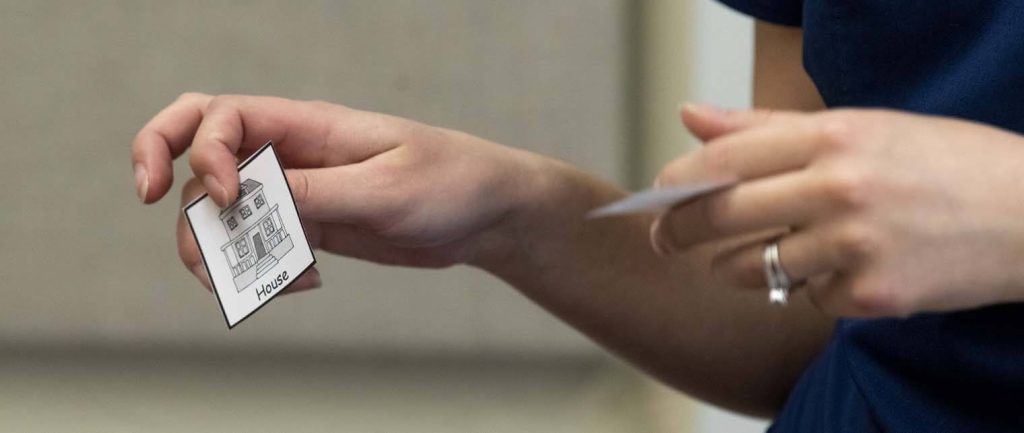 A photo of a hand holding a flash card with a house on it