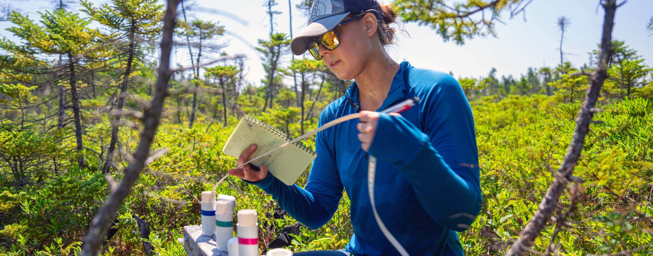 A photo of a student in a bog with research equipment