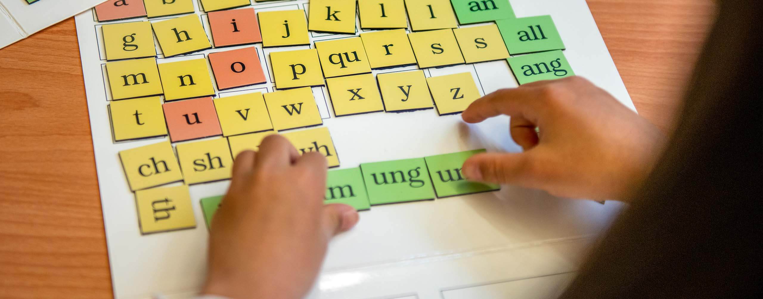 A photo of hands and letter tiles