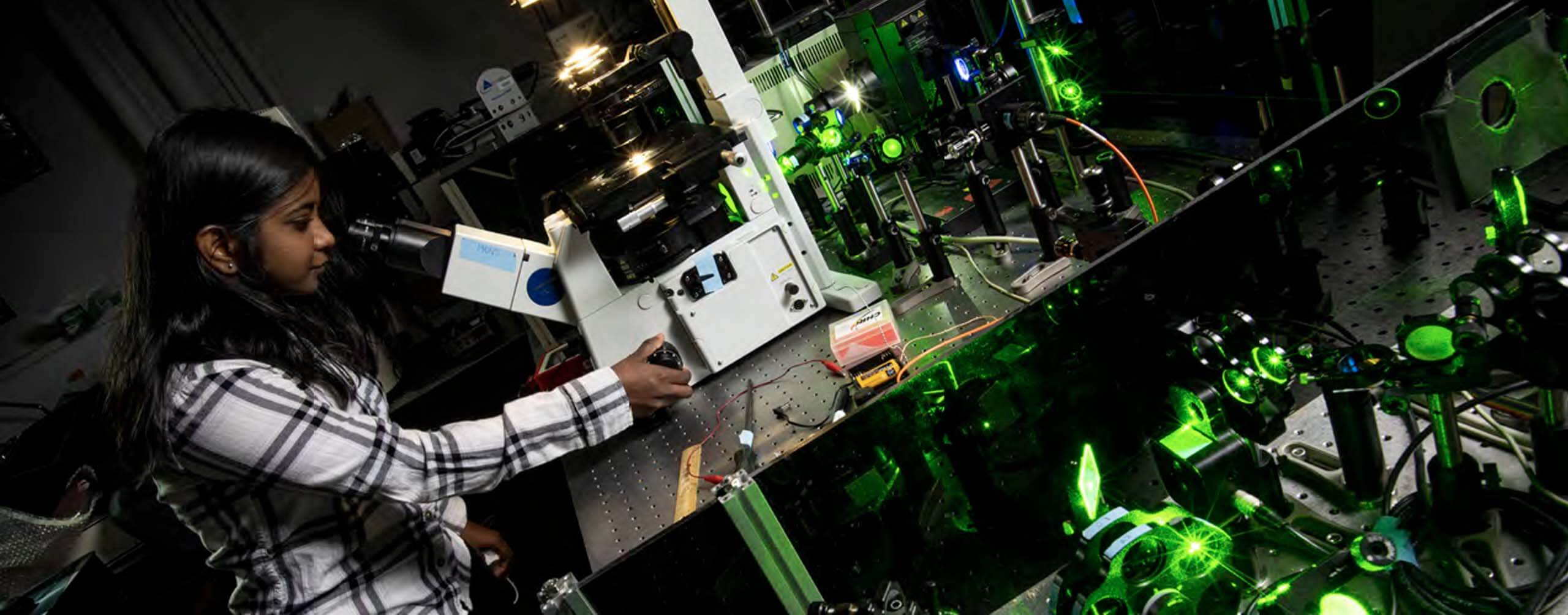 A photo of a person looking through a microscope